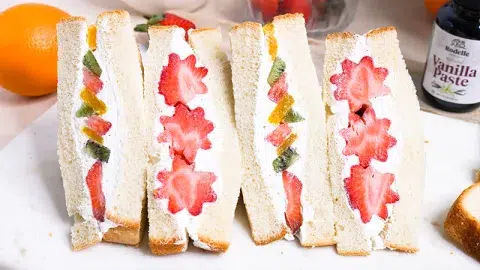 Two Japanese Fruit Whipped Cream Sandwiches cut in half showing a fruit pattern of strawberries, kiwi, and orange.