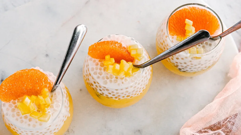 Vanilla and pomelo pudding with sago tapioca pearls in glasses with spoon on neutral background