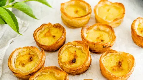 Egg tarts. Crispy golden brown pastry filled with egg custard on neutral background