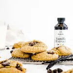Carmel brown colored chocolate chip cookies on cooling rack with vanilla beans and vanilla extract