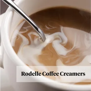 coffee creamer being stirred into coffee in white mug