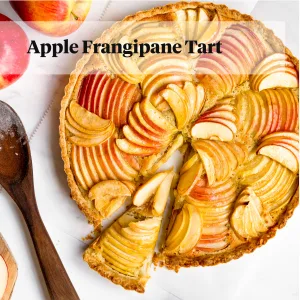 Apple tart sliced on marble backdrop with apples around