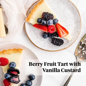 Vanilla tart with berries sliced on plate with serving spoon