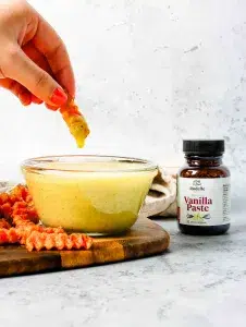 Vanilla aioli in clear dish on wooden cutting board with vibrant orange sweet potato fries