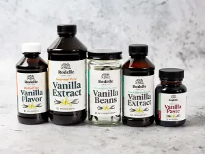 Family image of Rodelle products. From left to right, Rodelle alcohol free, Rodelle Gourmet Pure Vanilla Extract, Rodelle Gourmet Beans, Rodelle Pure Madagascar Bourbon Vanilla Extract, and Rodelle Natural Vanilla paste. All products lay on top of a gray textured background.