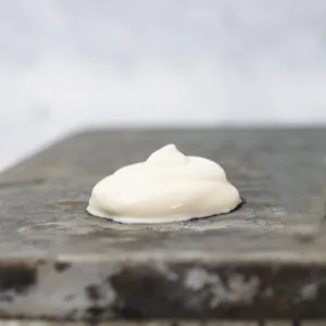 A piped blob of under beaten whipped cream on a gray textured pan.