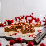 Peppermint Sugar Cookies - slices laying down on a parchment paper on top of a cookie tray. Surrounding the peppermint sugar cookies are red berries on branches and faerie lights.