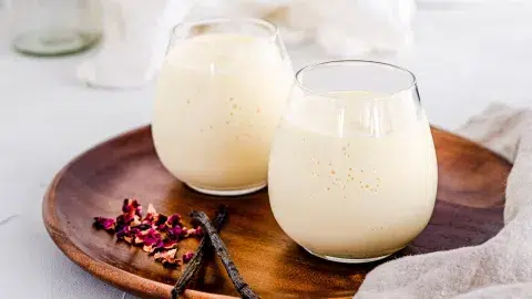 Vanilla mango smoothie in short cups on wooden background