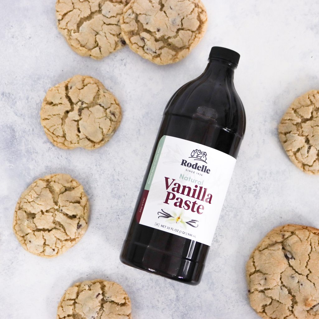 32 ounce sized bottle of vanilla paste on neutral background surrounded by cookies
