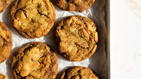 close up top shot of a group of chai apple cheesecake cookies with strong sunlight coming from upper right that's casting shadows. the photo feels warm and you can see the bits of apple and also the cream cheese swirl in each cookie