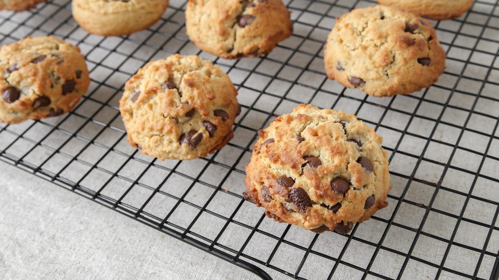 close up shot of a small batch chocolate chip cookies laying on a cooling rack. The table is a cool light gray color.